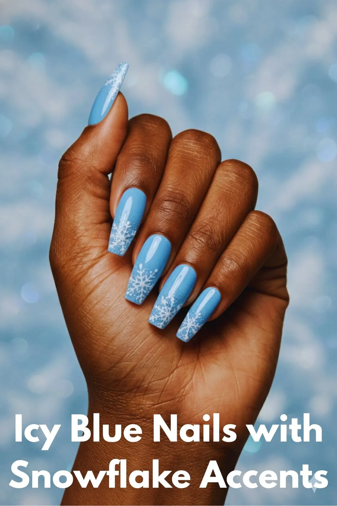 A hand displaying long, coffin-shaped acrylic nails painted in an icy blue color with delicate white snowflake designs.